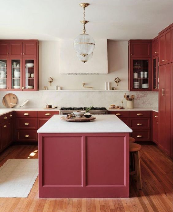 a refined burgundy kitchen with shaker cabinets, white countertops, gold fixtures and chic sphere pendant lamps