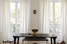 a refined dining space with molding and chevron flooring, a black table, stools and a bench and some lamps is pure elegance