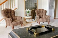 a refined living room with a statement mirror in a gilded frame, vintage leopard print chairs, a dark coffee table that echoes with the mirror in its shape