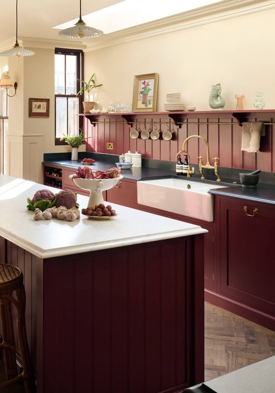 a refined vintage kitchen with burgundy cabinets and a beadboard backsplash, black and white countertops and vintage fixtures