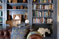 a row of navy arched bookcases, a desk and a chair, a brown leather sofa, lamps and cool decor