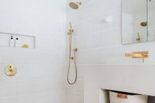 a serene white bathroom with a terracotta tile floor, a large vanity, a sink and a niche in the shower, an arched mirror