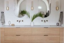 a sink space with an arched niche, a vanity, mirrors, a terracotta tile floor and chic gold wall sconces