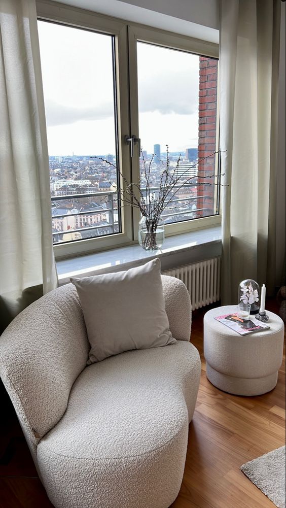 a small and lovely boucle loveseat, a matching pouf are a beautiful combo for any window nook