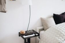 a small black nightstand of a whimsical shape, with a book stand and a niche is a cool idea for a Scandinavian space