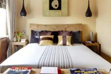 a small eclectic bedroom with a wooden bed, black pendant lamps, catchy printed textiles and a cool artwork with a touch of Asia