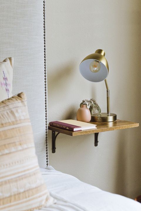 a small shelf as a nightstand with a vase, a book and a lamp is all you need for a small bedroom