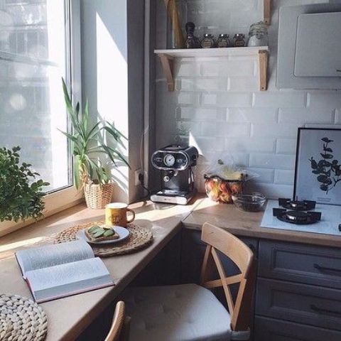 a small white kitchen with a white tile backsplash and butcherblock countertops, one of which is a windowsill that is a table and desk in one