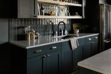 a soot kitchen with a grey stacked tile backsplash, white countertops and black fixtures is a relaxing moody space