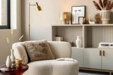 a stylish and refine dnook with a neutral storage unit, a white boucle chair, a glass side table and some chic decor