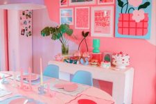 a super bold dopamine decor dining room with hot pink walls, white tables and blue chairs, a lilac pendant lamp, a bright gallery wall and bold decor