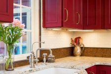 a super bold red vintage kitchen with two types of tiles on the backsplash and stone countertops looks very chic and elegant
