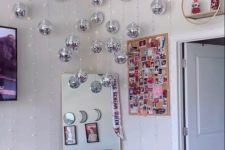 a teen room with a floor mirror in the corner and a whole arrangement of silver disco balls for a bit of fun and light