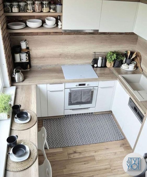 a tiny Scandinavian kitchen with sleek white cabinets, butcherblock countertops and a backsplash and a windowsill table plus stools