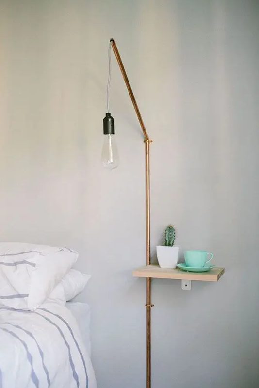 a tiny nightstand and a wall lamp with a copper tube are a great combo for a small Scandinavian bedroom