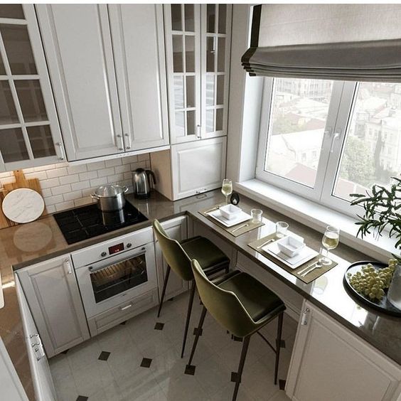 a tiny white kitchen with built-in lights, a countertop as a windowsill and a dining table, green stools