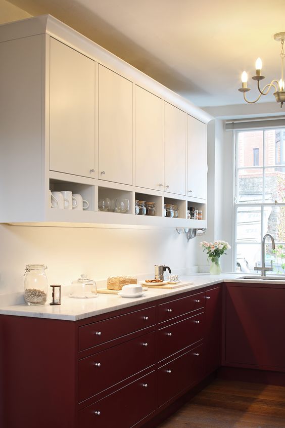 A two tone kitchen with upper white and lower burgundy cabinets, white countertops and built in lights is amazing