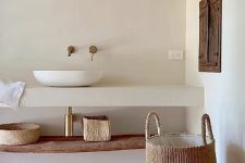 a wabi-sabi meets Mediterranean bathroom in white, with a herringbone terracotta floor, an open vanity and a basket