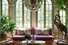a whimsical living room with arched window, potted plants, rattan furniture, a quirky table and a large disco balls