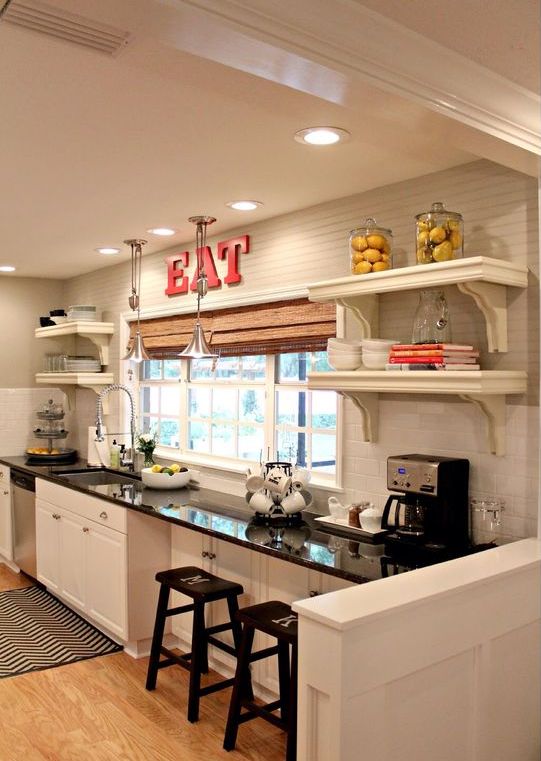 a white farmhouse kitchen with a black countertop that doubles as a table for eating at the window or having coffee