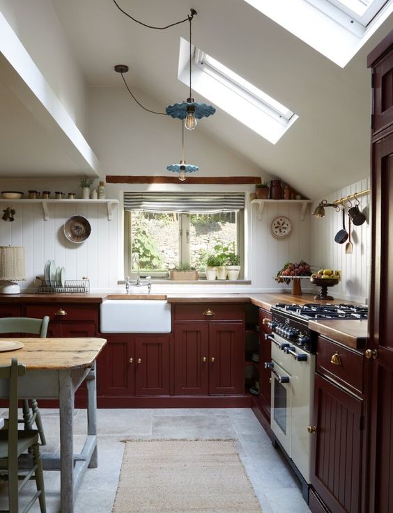 an English country kitchen with butcherblock countertops, skylights, a grey table and chairs