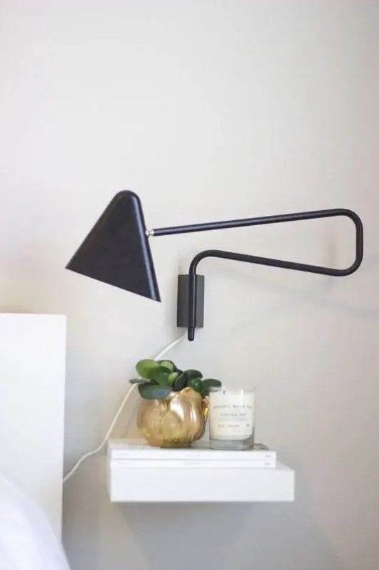 an IKEA Lack shelf attached to the wall as a nightstand to hold necessary things, and a black wall sconce