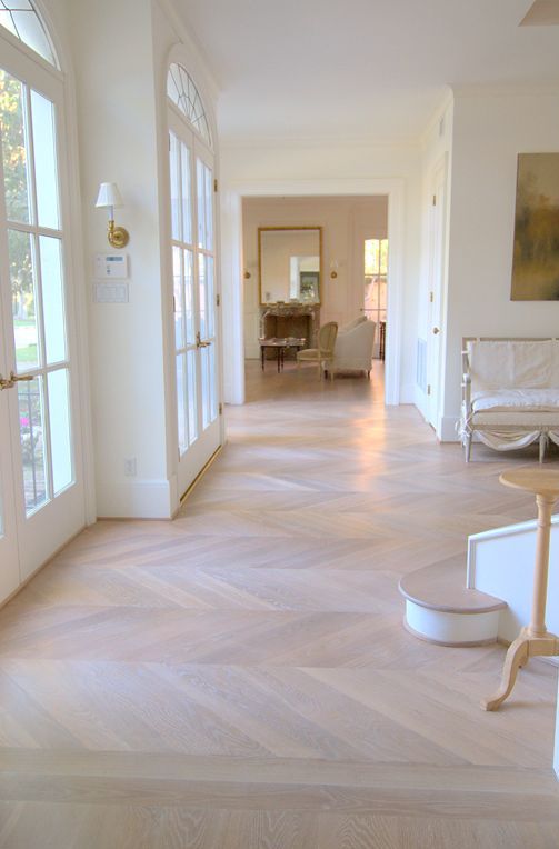 an all-neutral Provence-inspired space with all white everything and chevron floors plus some art