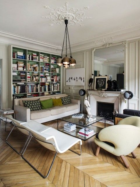 An eclectic Parisian chic living room with a fireplace, built in shelves, neutral seating furniture, a coffee table and lamps