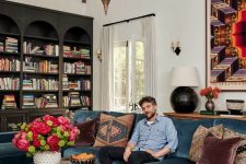 an eclectic living room with black arched bookcases, a navy sectional, a Moroccan table and Moroccan pendant lamps