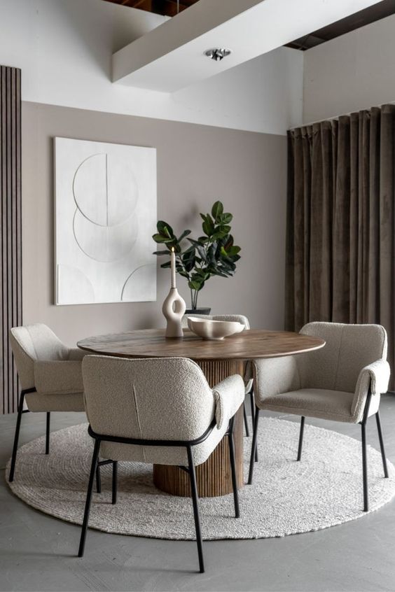 an elegant dining space with a stained table, neutral boucle chairs, chic decor, a potted plant and an oversized artwork