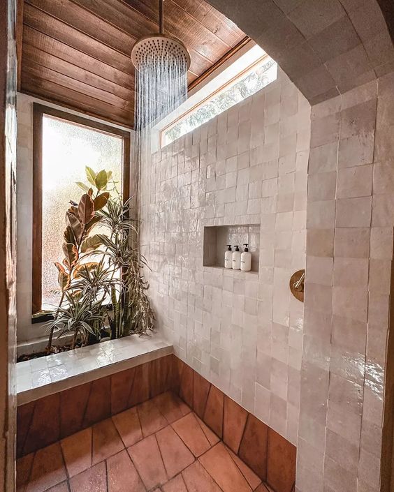 an eye-catchy bathroom with windows, neutral Zellige tiles and terracotta ones, a shower space with greenery