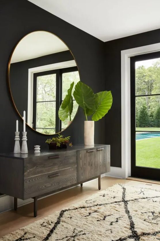 an oversized round mirror in a copper frame makes the moody entryway large and adds a trendy metallic touch