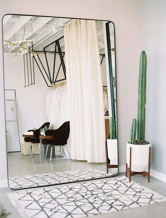 an oversized square mirror with curved corners takes a whole wall is a lovely idea for a boho entryway