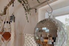 boho home decor with a disco ball hanging on the window, a macrame piece, some planters and greenery