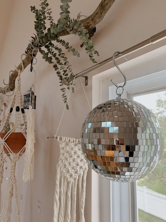 boho home decor with a disco ball hanging on the window, a macrame piece, some planters and greenery