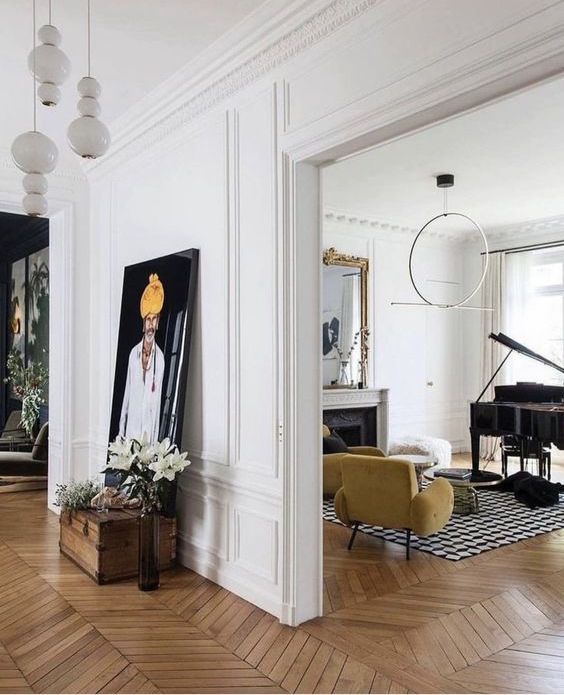 bold and contrasting spaces with chevron floors and molding, a fireplace, yellow seating furniture, some decor and artwork