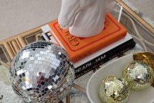 coffee table decor with a large silver disco ball and smaller gold ones, coffee table books and a horse head on top is amazing