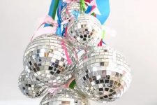 disco balls hanging on bright ribbons are amazing to style your space, hang them on a chandelier