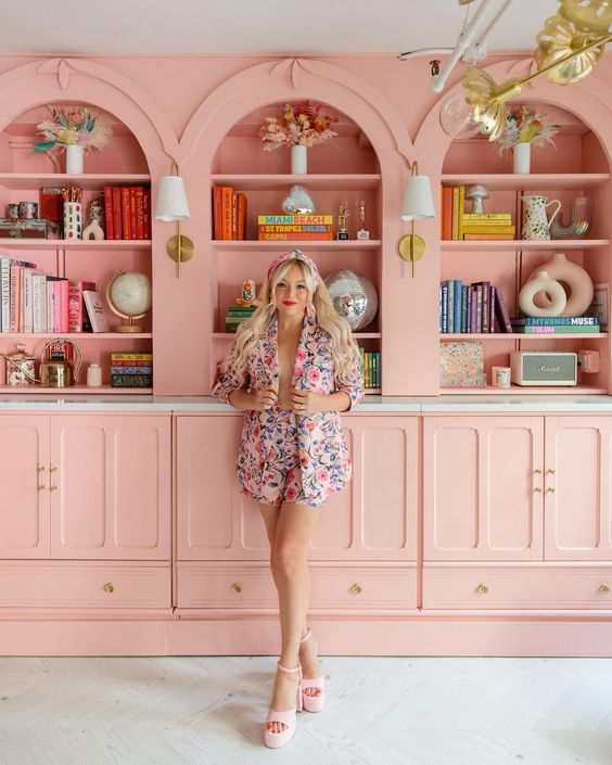 Light pink built in arched bookcases with bright books and chic decor are amazing for a bright and cool space