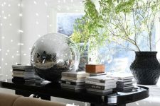 refined decor with a large black table, a lot of coffee tables, greenery in a vase and a large disco ball is amazing