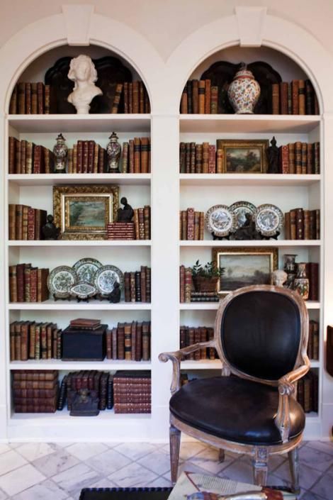 refined vintage white bookcases with books and vintage decor, a vintage black chair are a chic combo
