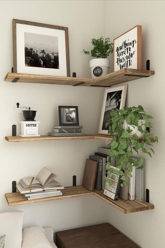 stained floating shelves with artwork, photos, books and potted plants are amazing to style a modern space