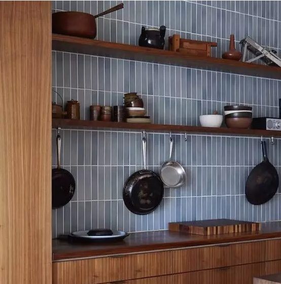 Warm toned wooden cabinets paired with a light blue skinny tile backsplash look contrasting and refreshed