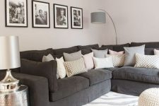 a Scandinavian living room with a graphite grey sofa and lots of pillows, a printed rug, white poufs and a floor lamp plus a gallery wall