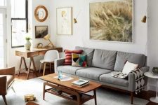 a Scandinavian living room with a stained trestle desk, a grey mid-century modern cotton sofa, a stained coffee table and a gallery wall