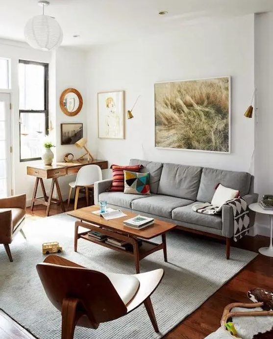 a Scandinavian living room with a stained trestle desk, a grey mid-century modern cotton sofa, a stained coffee table and a gallery wall