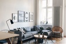 a Scandinavian space with a herringbone floor, a grey sectional sofa, coffee tables, a gallery wall and pendant lamps