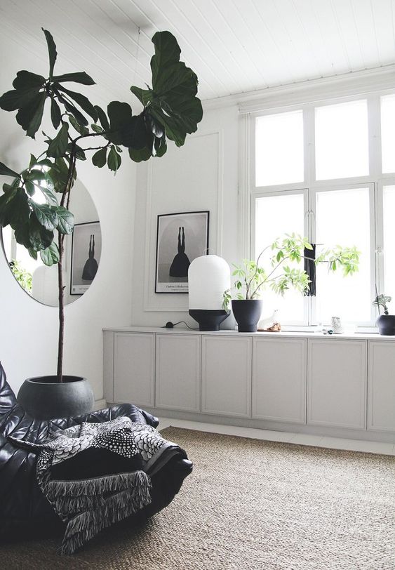 a Scandinavian space with light greey IKEA Metod cabinets, some lovely decor, a potted tree and a black chair