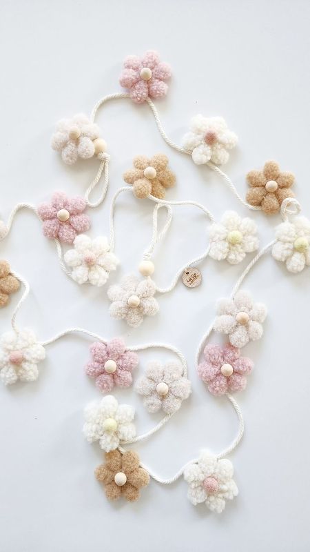 a beautiful flower garland made of pompoms and wooden beads looks amazing and will be nice for spring