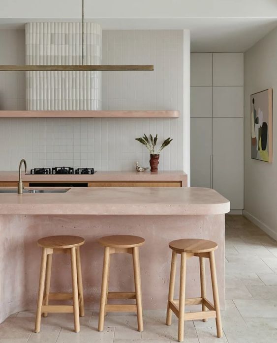 a beautiful modern kitchen with stained cabinets and pink countertops, a pink kitchen island, a fluted hood and wooden stools